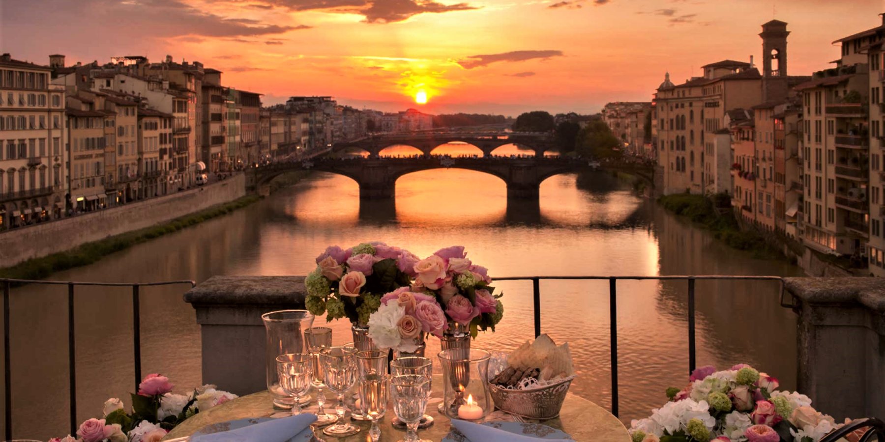Picture of a dining table infront of a river at sunset