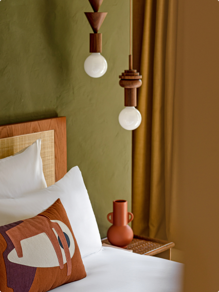Elegant bed adorned with plump pillows, accompanied by a graceful lamp
