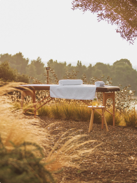 An open air massage table surrounded by greenery