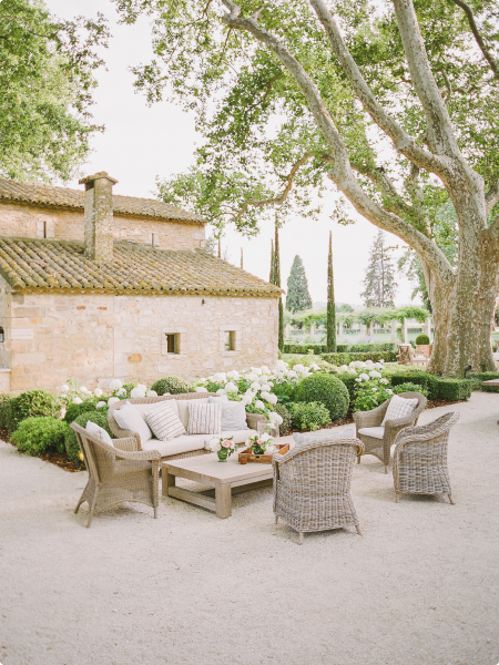 A stone patio with wicker furniture and trees.